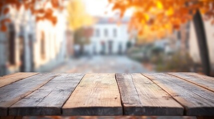 An empty wooden table is positioned in front of a blurred backdrop of an autumn city street filled with colorful leaves