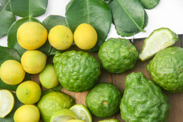 Pile of kaffir limes and limes or Citrus aurantifolia arranged, on leaves background