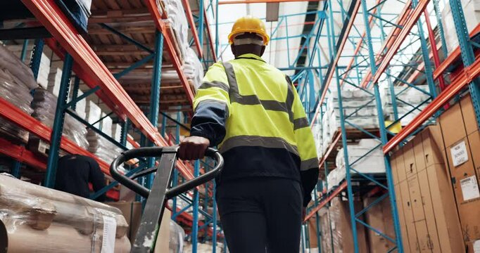 Logistics, man or worker with trolley in warehouse for package distribution, supply chain or delivery products. Back, inventory or person pulling a pallet jack in factory for storage stock or walking