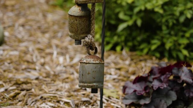 Slow motion look at decorative bells in a garden.
