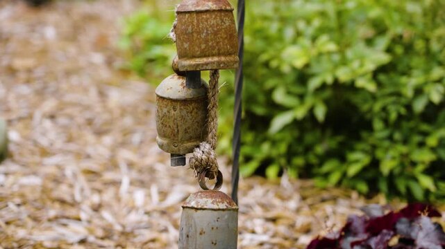 Camera slow motion footage with color look at decorative bells in a garden.