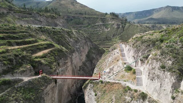 Flyover Colca Canyon footbridge in mountain terraces near Yanque, Peru