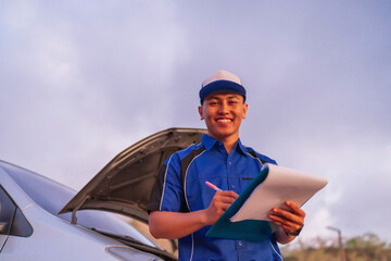 potrait of smiling male mechanic writing car problem on notes