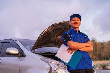 happy male car technician standing with crossing arm in front of car