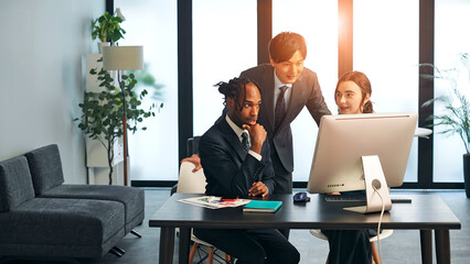 A group of multinational business people having a meeting about corporate management while looking at a computer in an office