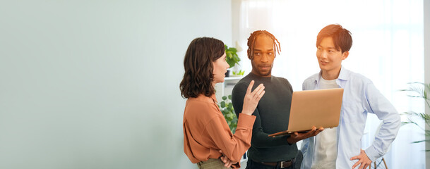 Multinational people in casual wear having a meeting about business management while looking at a...
