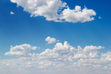 An azure sky filled with fluffy white cumulus clouds stretches.