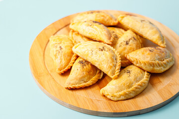 Curry puff pastry on wooden plate on blue background.