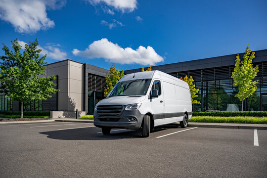 White cargo mini van making delivery to customer work place standing on the industrial parking lot