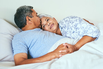 Relax, cuddle and senior couple in bed with kiss for love, support and marriage connection on weekend. Elderly people, happy and affection with smile at home for retirement romance, bonding and peace