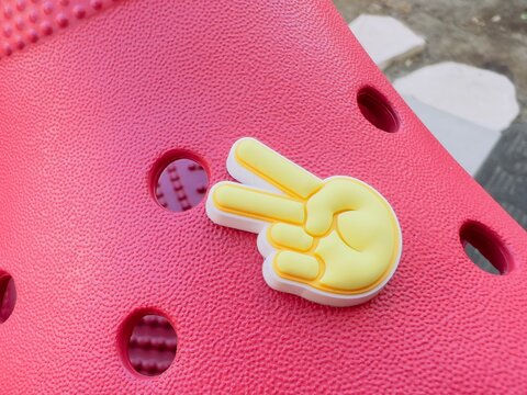 Peace gesture Crocs shoe charm closeup.