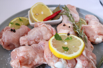 raw chicken wings with pepper and lemon on the plate