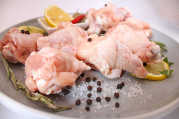 raw chicken wings with pepper and lemon on the plate