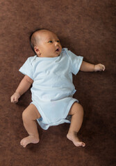 Close-up of a happy smiling baby on a sofa in a bright bedroom.