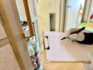 手すりの前でクリップボードに記入する軍手をはめた手