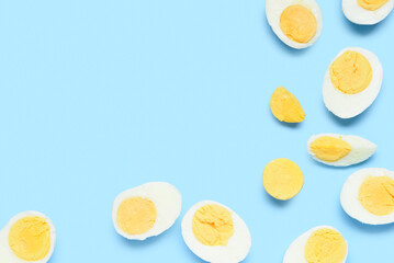 Halves of tasty boiled eggs with slice on blue background