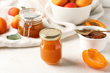 Jar with sweet apricot jam on white background