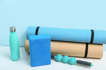 Different fitness equipment on white table near blue wall, closeup