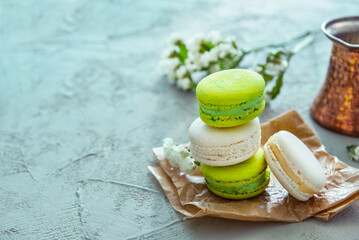 Baking paper with sweet macaroons and beautiful flowers on green table