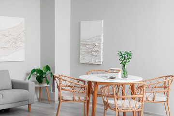 Interior of modern living room with paintings, grey sofa and dining table