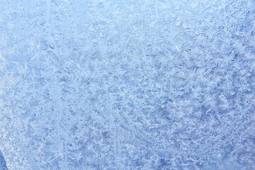 Frost patterns on frozen glass on a winter day. Winter frosty texture natural background