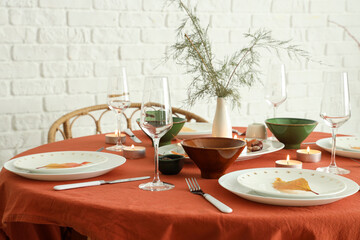 Autumn table setting with burning candles and dry leaves