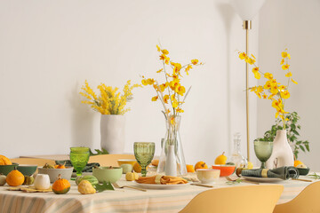 Autumn table setting with flowers and pumpkins in light dining room
