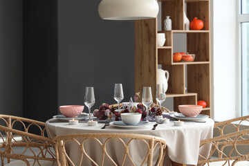 Autumn table setting with eucalyptus branches and burning candles in modern dining room