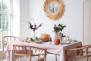 Autumn table setting decorated for Thanksgiving Day with pumpkins and eucalyptus branches in light dining room