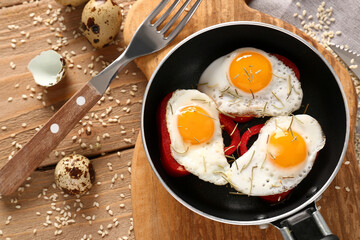 Frying pan with tasty quail eggs, fork and sesame seeds on wooden table