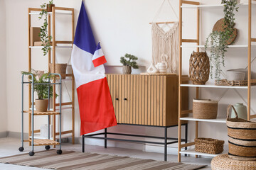 Interior of light living room with French flags, commode and shelf units
