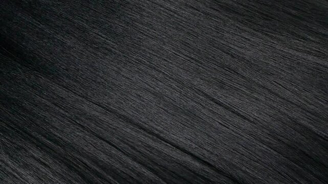 Closeup human long hair texture in slow motion, black straight hair background