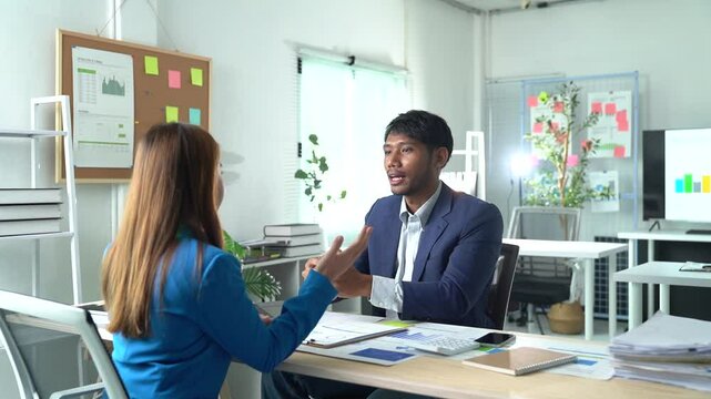 Businesswoman discussing with a businessman at an office desk, addressing issues while he makes excuses. Tension builds as they navigate a serious conversation about workplace challenges