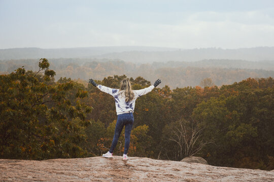 Girl standing on cliff overlooking scenic autumn mountain view