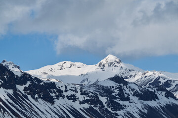 Fototapeta premium Frozen mountains under cloudy blue sky in wintertime