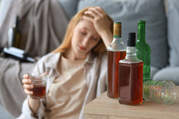 Young woman drinking alcohol at home. Concept of alcoholism