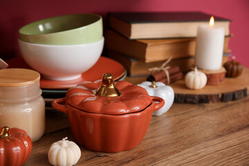 Dishes, books and autumn decor on wooden table