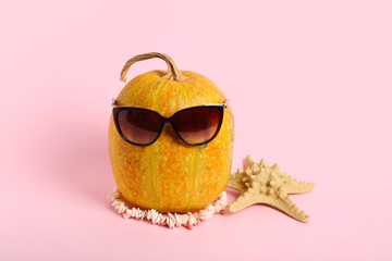 Halloween pumpkin, starfish and sunglasses on pink background