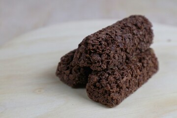 Delicious healthy cereal bar from whole wheat and chocolate with flying crumbs isolated on wooden table background.