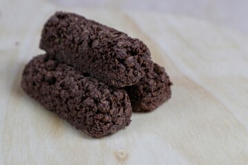 Delicious healthy cereal bar from whole wheat and chocolate with flying crumbs isolated on wooden table background.