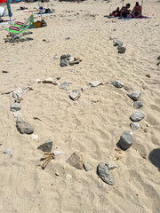 A unique heart shape crafted from rocks situated on a beautiful sandy beach, creating an interesting contrast in the landscape