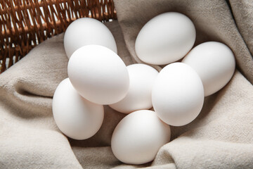 Wicker basket with raw chicken eggs, closeup