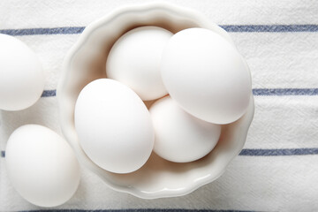 Bowl with raw chicken eggs on napkin