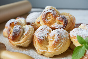 Homemade buns sprinkled with powdered sugar on a light background.
