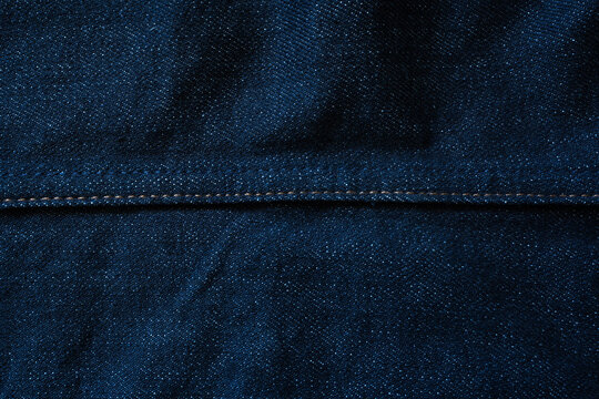 Raw blue denim jeans texture background with seam line in the middle
