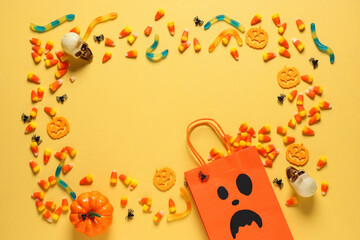Frame made of shopping bag, different candies and Halloween decorations on yellow background