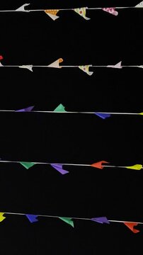 Shot of coloured birthday celebration pennants waving in the in blue sky. Colorful triangle bunting flags or banderitas hanging and blown by wind against blue sky. Celebration and fiesta concepts.