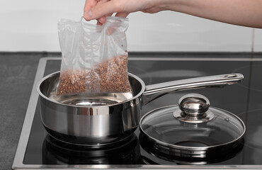 Gospodyni domowa wkładająca do garnka kaszę gryczaną w plastikowych torebkach do gotowania 