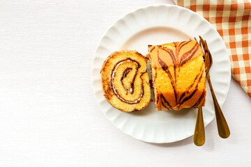 Coffee break roll cake in a white plate on white background, top view food table with free copy space