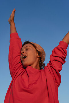 Smiling happy woman against blue sky background.